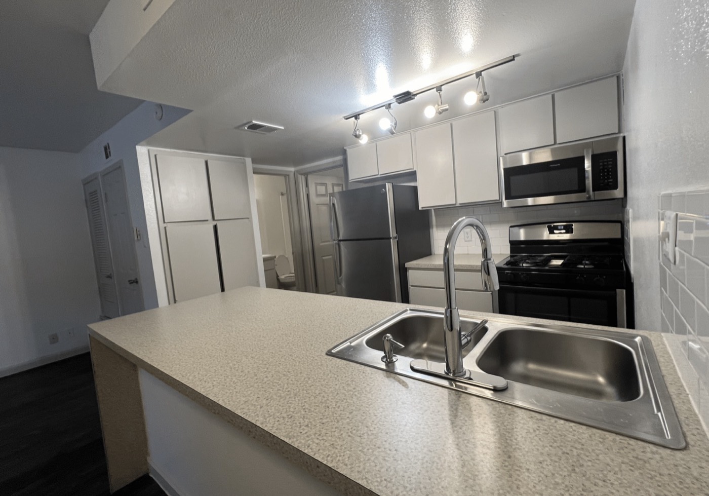 Kitchen with island, stainless appliances and track lighting